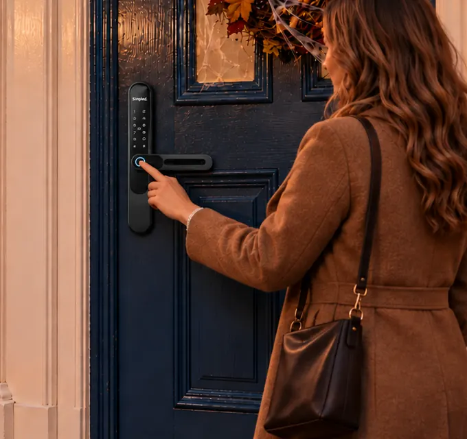 A fingertip on the reader of a Simpled smart lock on a navy front door